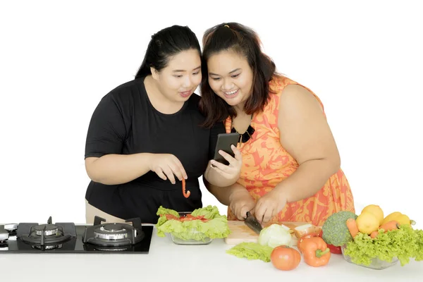 Duas mulheres fazendo uma salada com um smartphone — Fotografia de Stock