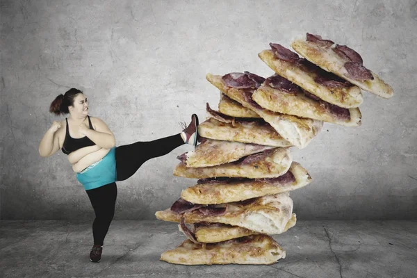 Mujer con sobrepeso pateando pila de pizza —  Fotos de Stock