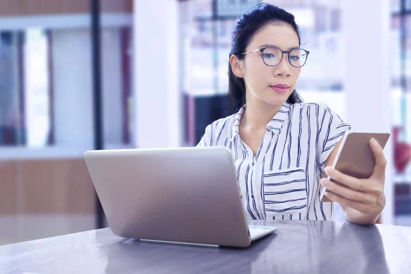 Empresária trabalhando com telefone celular e laptop — Fotografia de Stock