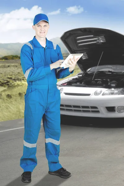 Amerykański mechanik naprawy uszkodzonego samochodu z tabletem — Zdjęcie stockowe