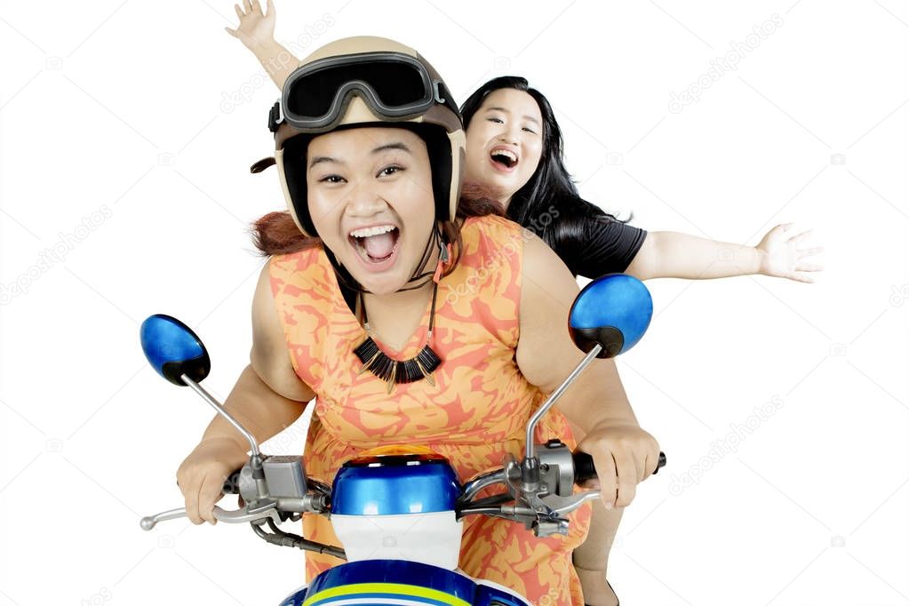 Two fat women riding a motorbike on studio