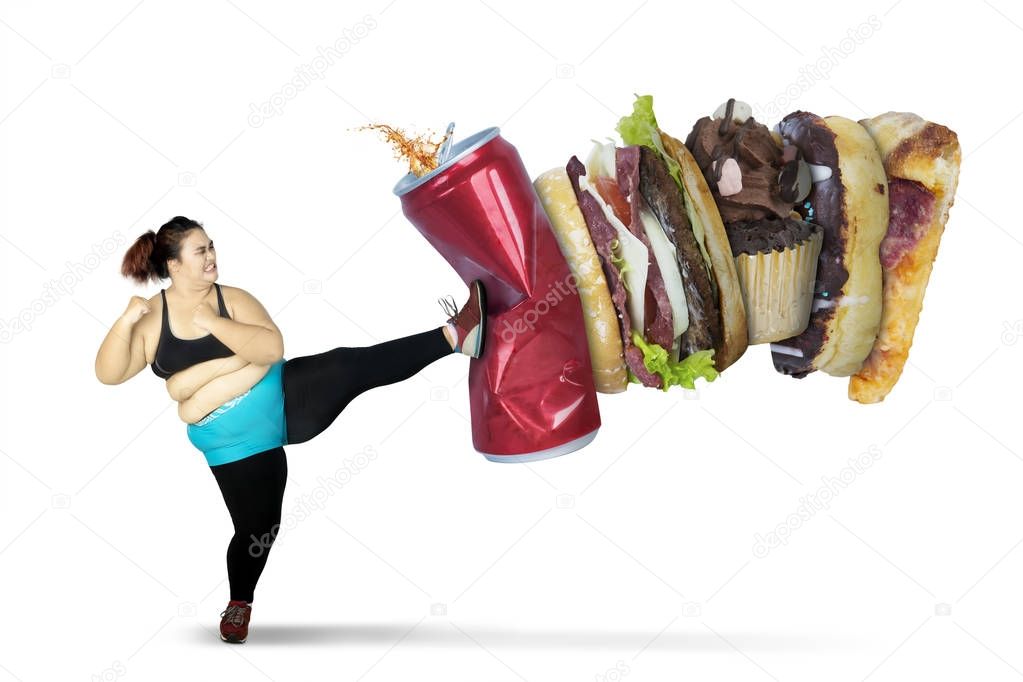 Overweight woman kicking soft drink and fast foods
