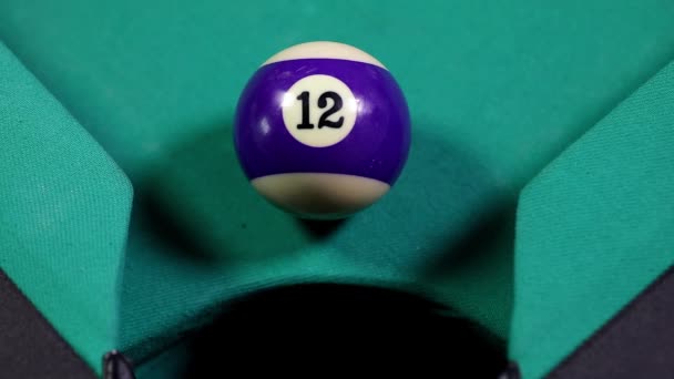 Gros plan d'une boule de billard numéro 12 de couleur pourpre entrer dans la poche du billard 