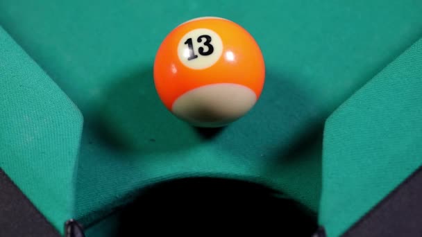 Macro shot d'une boule de billard orange avec le numéro treize entrer dans la poche du billard 
