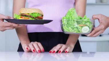 Diyet kavramı. Bilinmeyen kadının elleri hamburger reddeden ve salata bir kase alarak jest. 4 k çözünürlükte vurdu