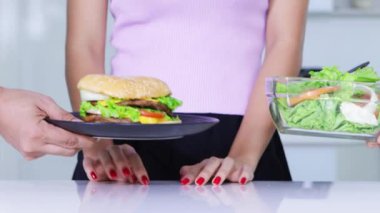 Diyet kavramı. Anonim kadın eller hamburger reddetme ve salata bir kase alarak jest. 4 k çözünürlükte vurdu