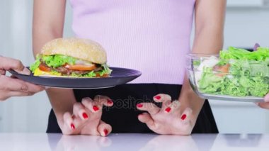 Diyet kavramı. Salata yemek reddederek ve hamburger seçme bilinmeyen kadın el jest kapatın. 4 k çözünürlükte vurdu