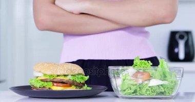 Diyet kavramı. Anonim kadın elinde bir kase salata seçimi kadar yakın ve bir tabak Burger reddediyorum. 4 k çözünürlükte vurdu