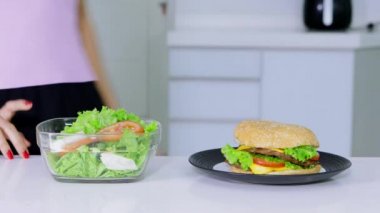 Diyet kavramı. Bilinmeyen kadın daha burger bir tabak salata bir kase alın için tercih. 4 k çözünürlükte vurdu