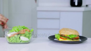 Diyet kavramı. Anonim kadın salata daha hamburger almak için tercih. 4 k çözünürlükte vurdu