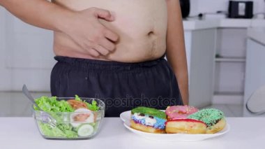 Diyet kavramı. Bilinmeyen kilolu adam al ve salata bir kase çörek yemek için karar vermek. 4 k çözünürlükte vurdu