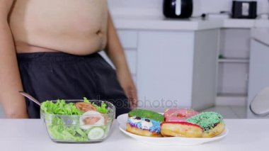 Diyet kavramı. Seçme meçhul kilolu adam ve bir tabak çörek veya abur cubur salata bir kase daha aç. 4 k çözünürlükte vurdu