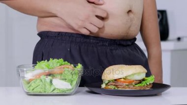 Diyet kavramı. Bilinmeyen kilolu adam seçme eller ve burger veya lokanta salata daha alın. 4 k çözünürlükte vurdu