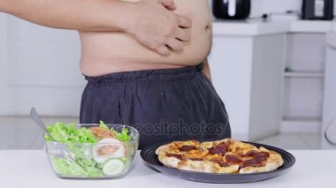 Diyet kavramı. Anonim kilolu adam almak ve bir tabak salata pizza bir tabak daha seçme. 4 k çözünürlükte vurdu