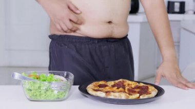 Diyet kavramı. Bilinmeyen kilolu adam bir tabak salata daha biberli pizza almaya karar vermeden. 4 k çözünürlükte vurdu