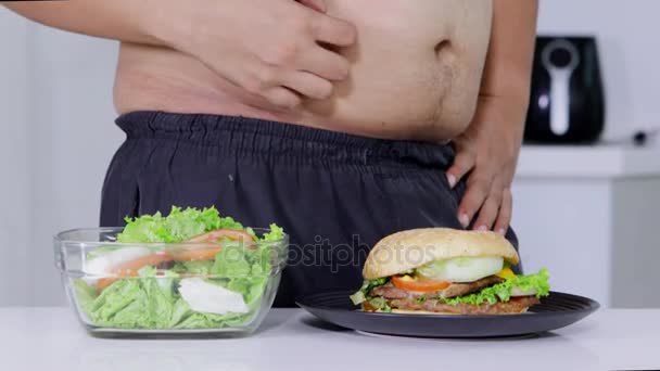 节食概念 不知名的超重男子选择汉堡或垃圾食品比一碗沙拉 分辨率拍摄 — 图库视频影像