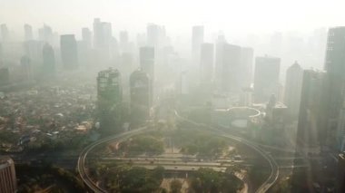 Jakarta - Endonezya. 26 Aralık 2017: Güzel hava bir kadeh yol kavşağı ve ileri uçan bir uçağın puslu sabah içinde gökdelenler. 4 k çözünürlükte vurdu