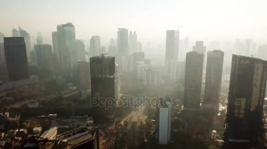 Jakarta - Endonezya. 26 Aralık 2017: Jakarta cityscape duman ya da geriye doğru uçan bir dron 4 k çözünürlükte çekim sis gökdelenler, yakınındaki puslu sabah hava görüntüsünü