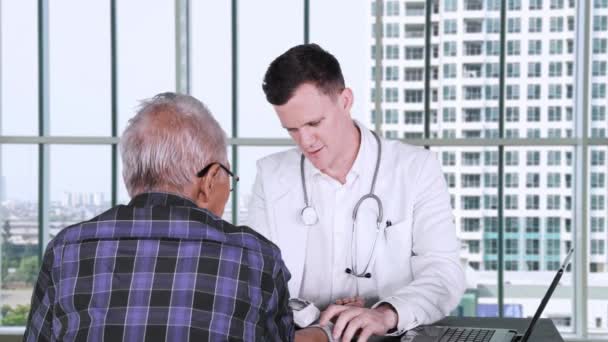 白种医生用血压计检查医生办公室的病人血压 — 图库视频影像