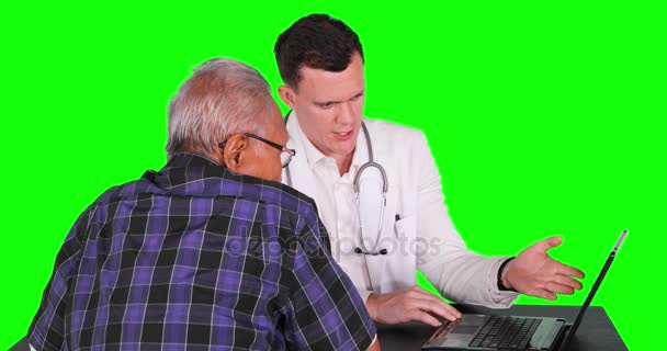 高齢患者に診断結果を説明するラップトップ コンピューターを使用して若い白人医者グリーン スクリーンの背景を持つ 解像度で撮影 — ストック動画