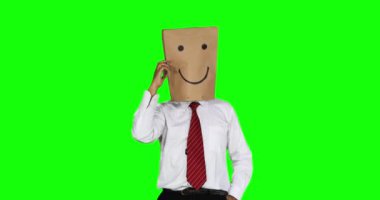 Bilinmeyen işadamı, kafasına kese kağıdı ile stüdyoda telefon görüşmesi dururken. 4 k çözünürlüklü yeşil ekran arka planı ile vurdu