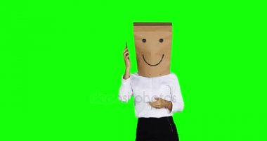 Kimliği belirsiz işkadını, kafasındaki kese kağıdı ile stüdyoda bir telefon görüşmesi. 4 k çözünürlüklü yeşil ekran arka planı ile vurdu