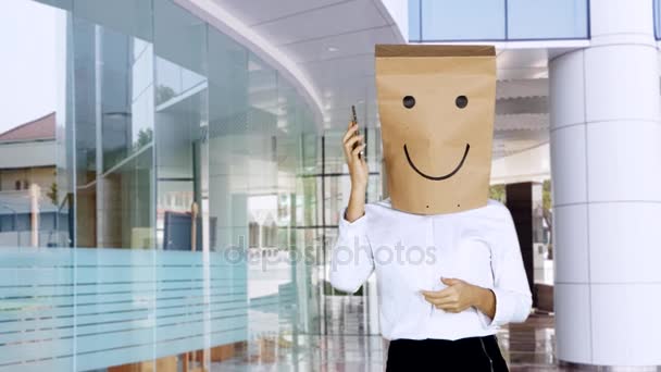 オフィス ロビーに立っている間電話をかける彼女の頭の上の紙袋と不明な実業家 — ストック動画