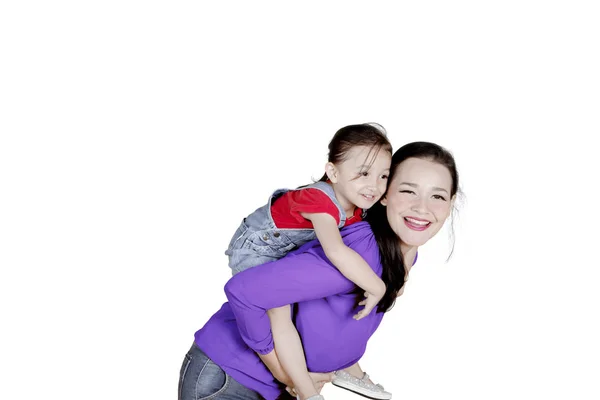 Mãe piggybacking sua filha no estúdio — Fotografia de Stock