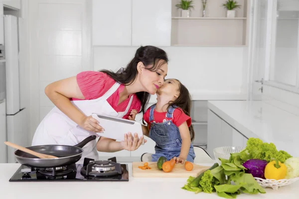 Criança beijando sua mãe na cozinha — Fotografia de Stock