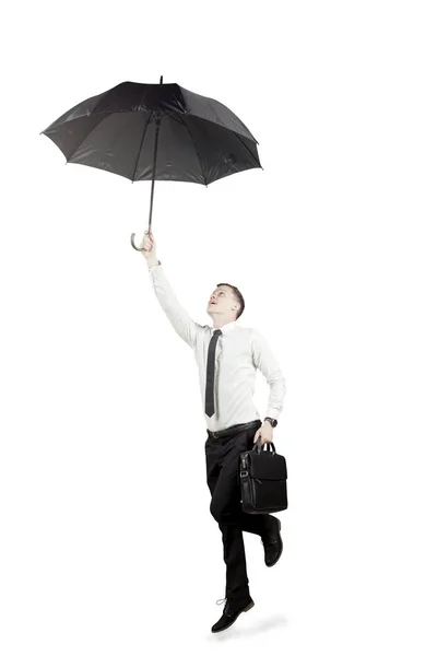Homem de negócios caucasiano voando com um guarda-chuva no estúdio — Fotografia de Stock