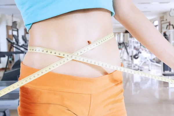 Young woman measuring her slim tummy — Stock Photo, Image