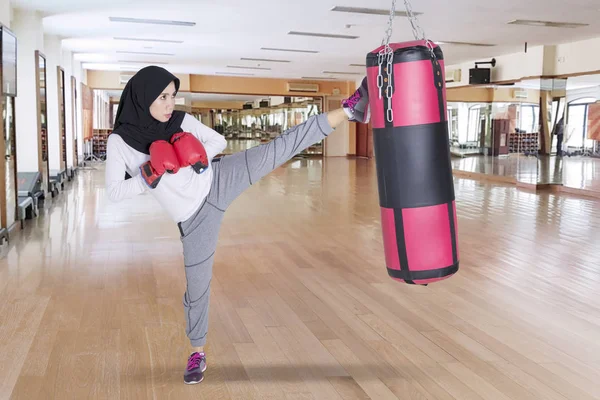 Jeune femme donnant un coup de pied dans un sac de boxe — Photo