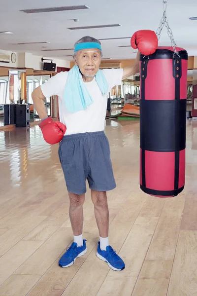 Old man leaning with a boxing sack — Stock Photo, Image