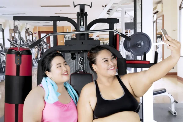 Mujeres obesas con teléfono inteligente en el centro de gimnasio — Foto de Stock