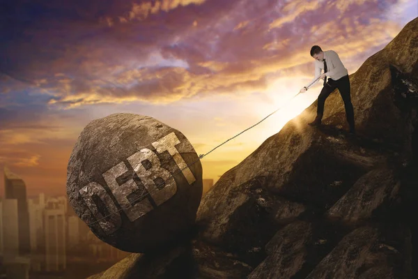 Male entrepreneur pulling debt word on cliff — Stock Photo, Image