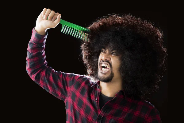 African man combs his frizzy hair