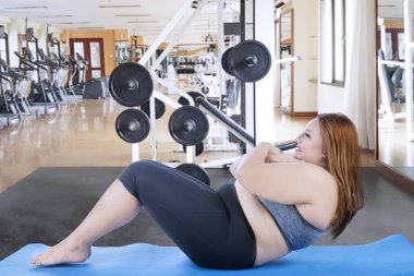 Spor salonunda mekik çeken şişman kadın. 