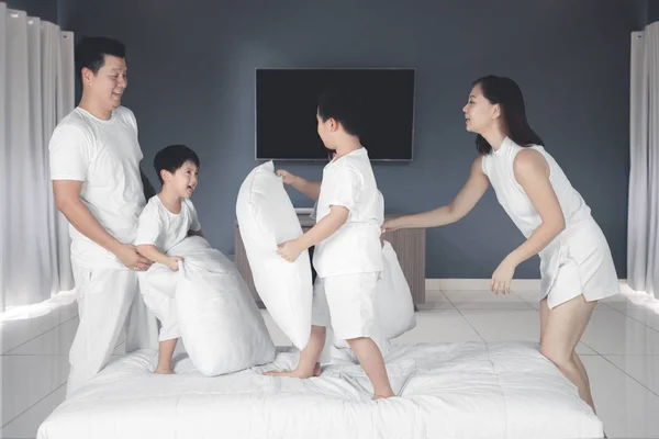 Giovane famiglia gioca con i cuscini in camera da letto — Foto Stock