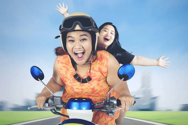 Due donne obese cavalcare scooter lungo la strada della città — Foto Stock