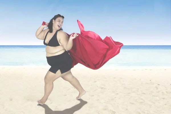 Obézní žena s červeným šátkem na pobřeží — Stock fotografie
