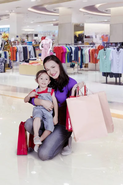 Madre en cuclillas con el niño en la tienda de ropa — Foto de Stock
