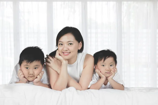 Moeder met haar zoons op het bed liggen — Stockfoto