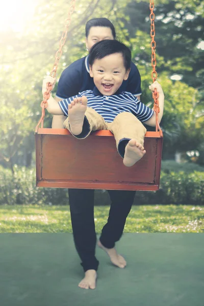 Menino tocando um swing com seu pai — Fotografia de Stock