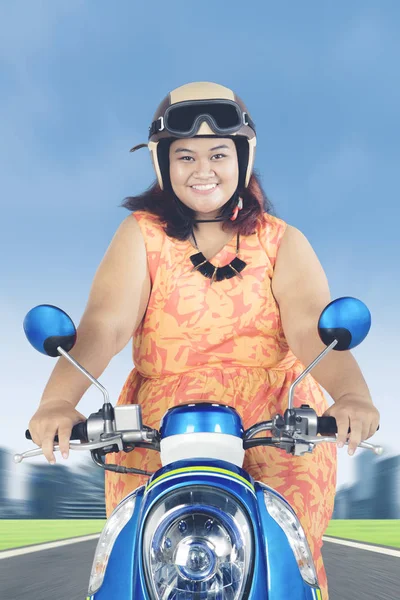 Mujer gorda montando un scooter en el camino — Foto de Stock