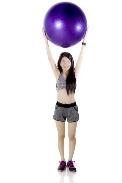 Chinese woman lifting a fitness ball on studio — Stock Photo, Image