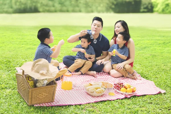 Família chinesa brincando com sabão bolha no parque — Fotografia de Stock