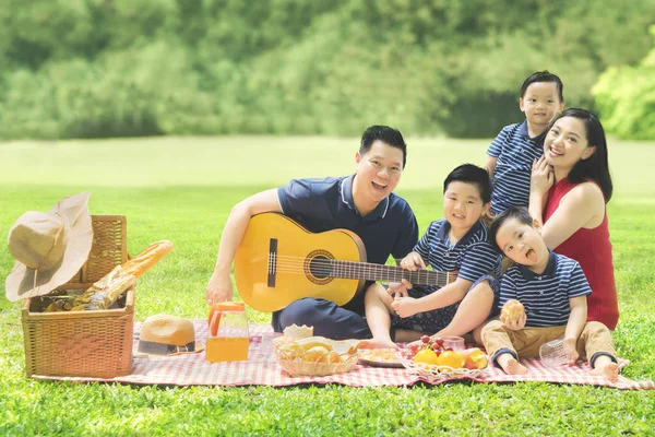 Chinese family playing a guitar in the park — Stock Photo, Image