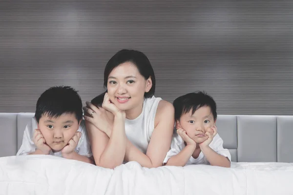 Mooie vrouw met haar zoons op het bed — Stockfoto