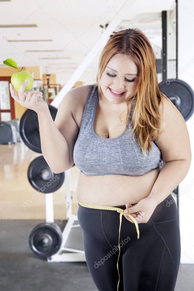 Obese woman with measure tape and apple