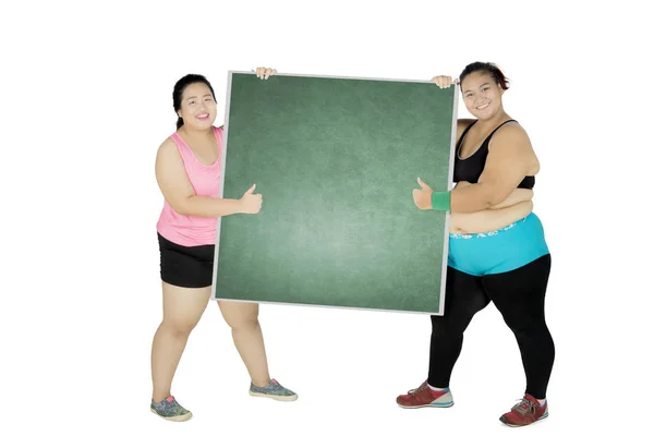 Two obese women with chalkboard on studio — Stock Photo, Image